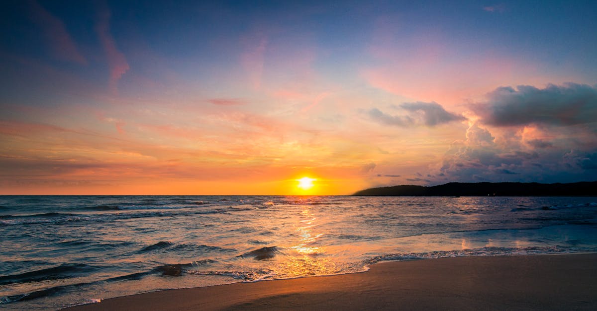Serene beach view at sunset with vibrant sky reflecting on the water.