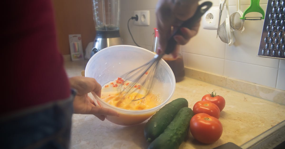 Cooking scene with whisking ingredients and fresh vegetables in a kitchen.