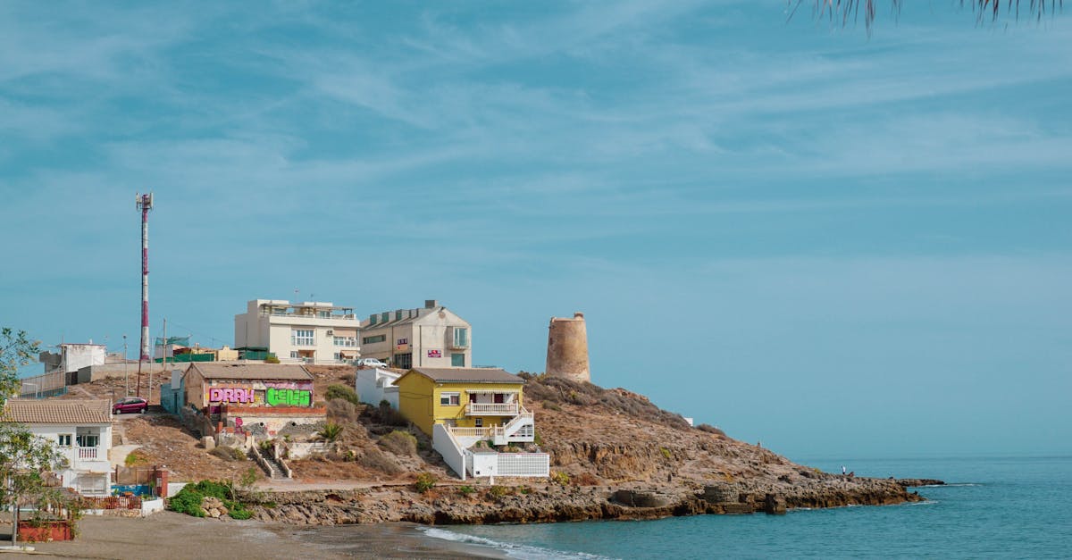 Charming coastal village with colorful houses and a sandy beach under a blue sky.