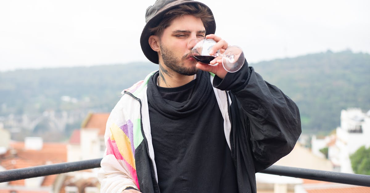 Young man with beard savoring wine on a scenic rooftop in Portugal.