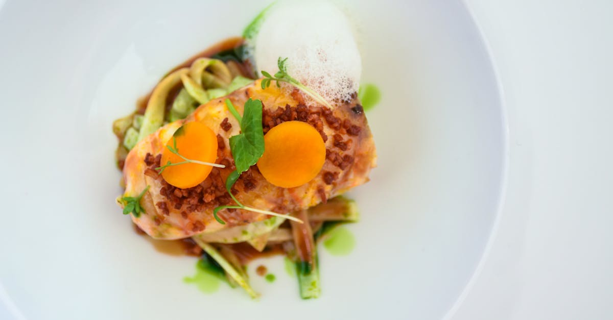 A beautifully plated gourmet dish featuring vegetables garnished with delicate foam and sauce.