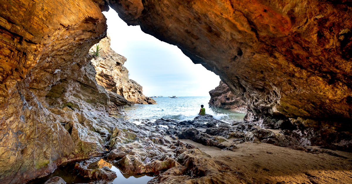 Explore the stunning view from a rocky beach cave, revealing the serene sea beyond.