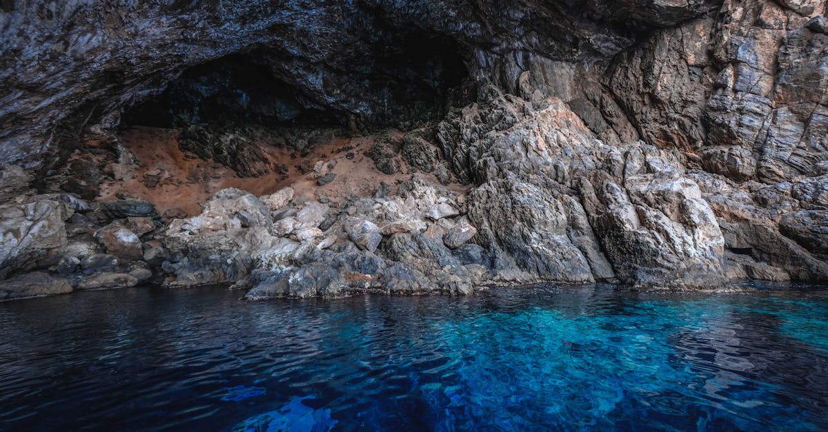 Clear blue sea with ripples on transparent water flowing through rough rocky cave