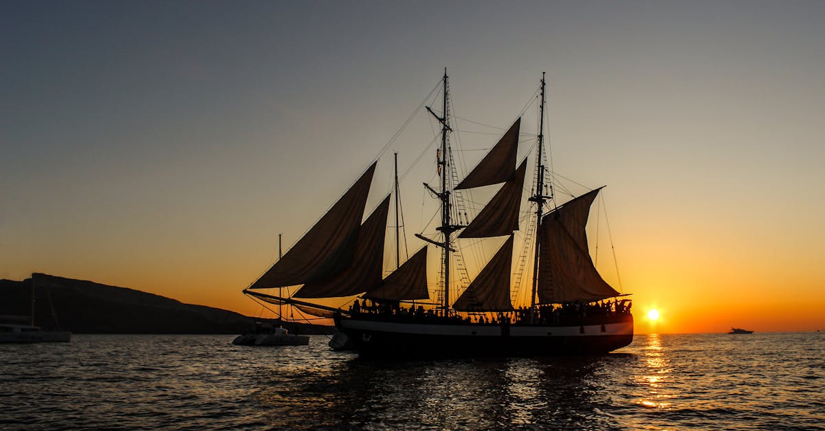 A silhouette of a classic sailing ship against a vibrant sunset over the ocean, perfect for travel themes.