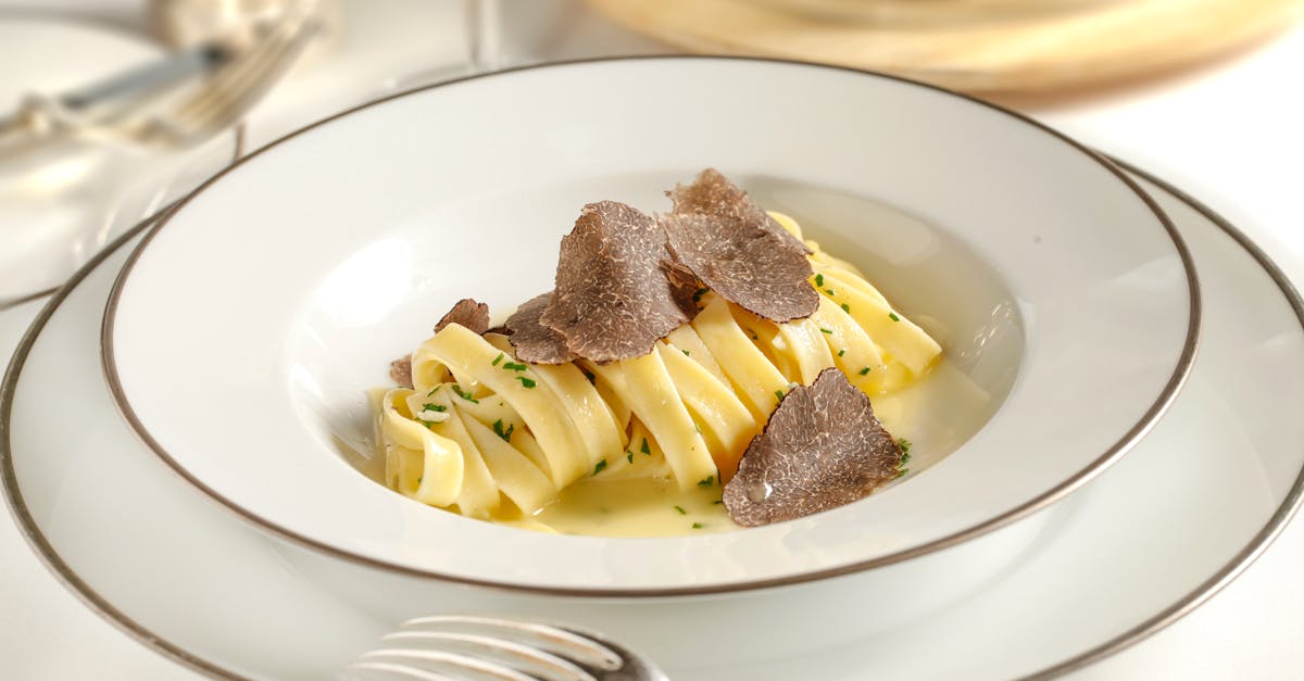 Close-up of gourmet pasta with truffle shavings served on a luxurious white plate, perfect for a fine dining experience.