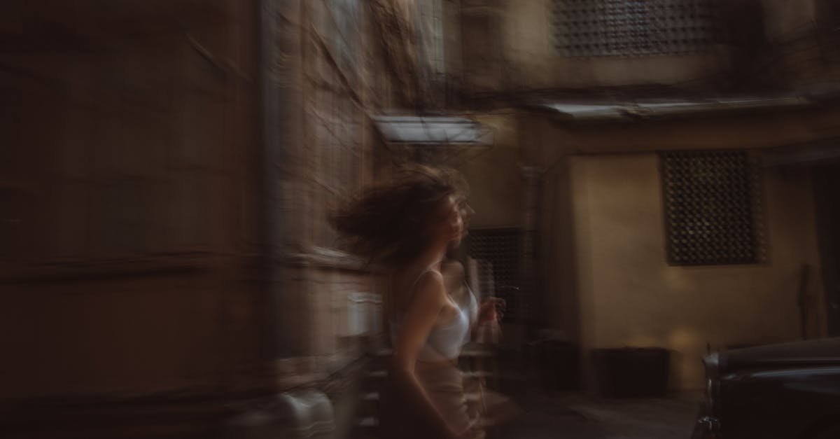 Blurred image of a woman running in an urban setting, capturing motion and mystery.