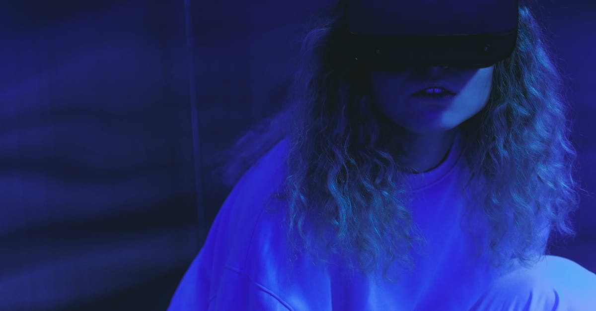 A woman wearing a VR headset enjoys a virtual reality experience in neon lighting.