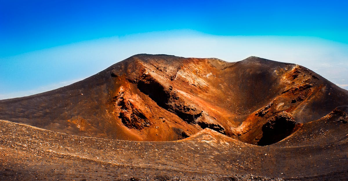 Explore the breathtaking volcanic crater landscape with vibrant colors under a clear blue sky in Sicily.