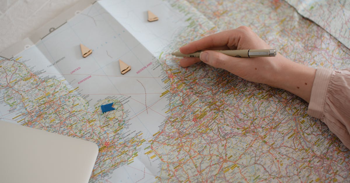 Hand holding pen over Europe map, planning travel route with markers.