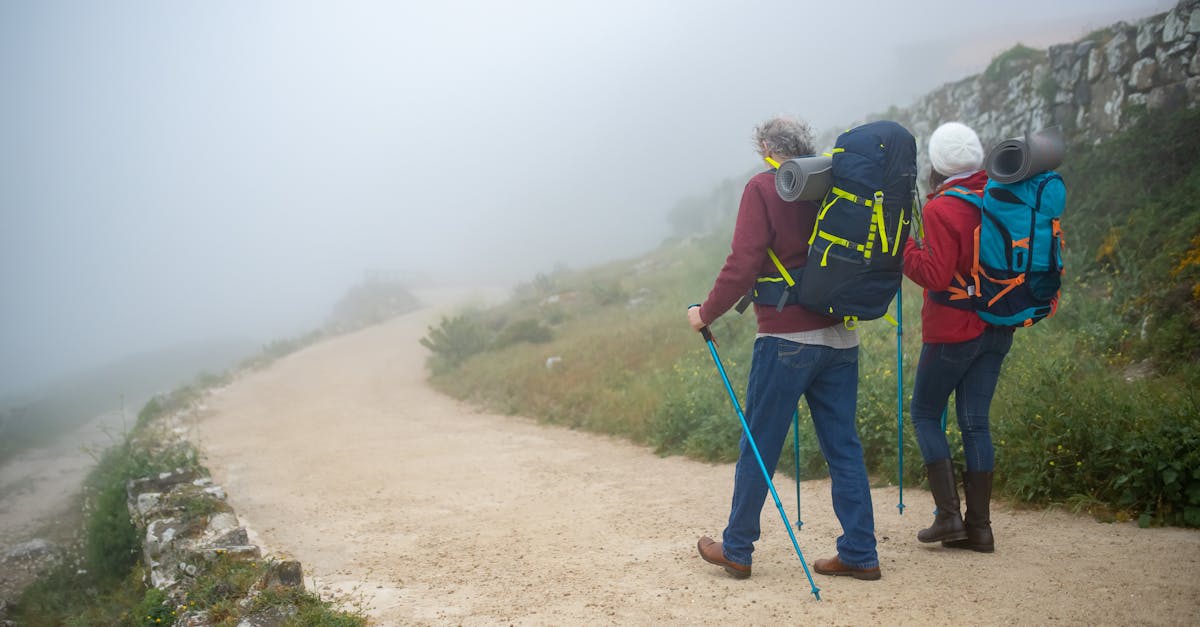 Couple hiking in foggy Portuguese countryside with backpacks, enjoying adventure walk.