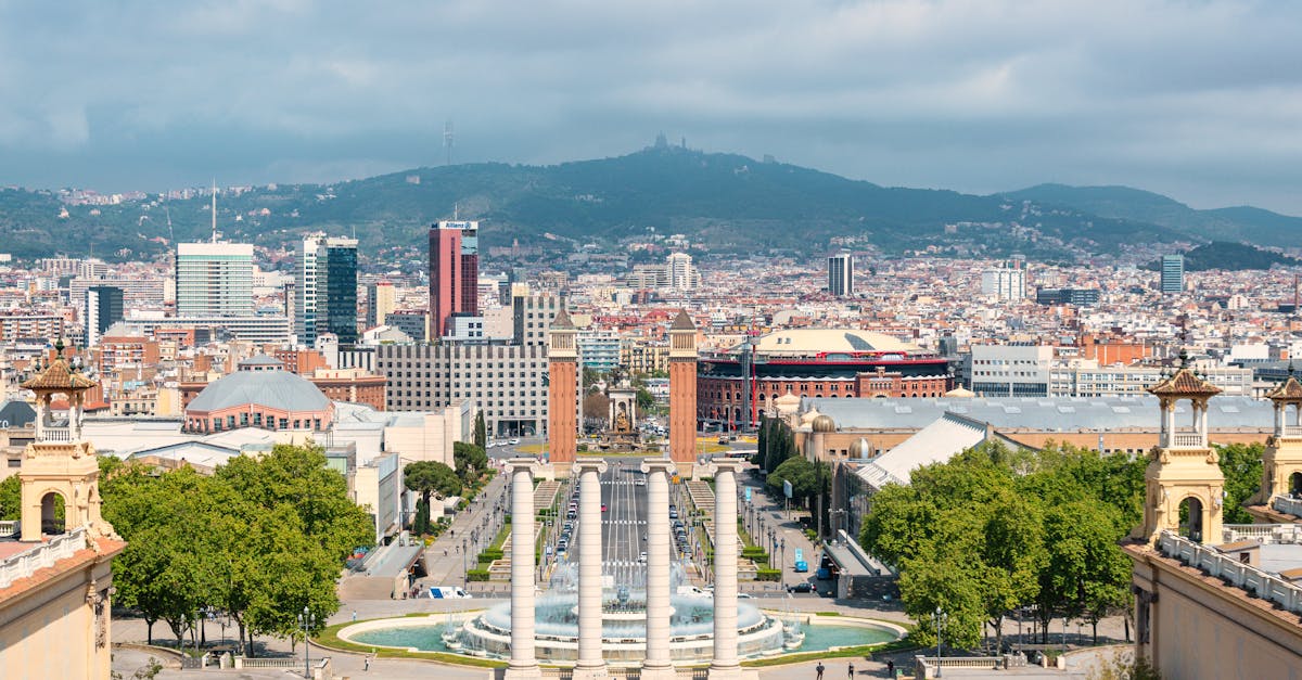 Panoramic view of Barcelona cityscape from Montjuïc Hill showcasing architecture and Sagrada Familia in the distance.