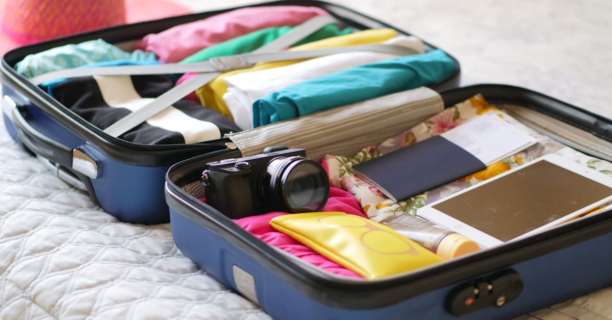 Open suitcase with camera, clothes, and passport, ready for a summer vacation.
