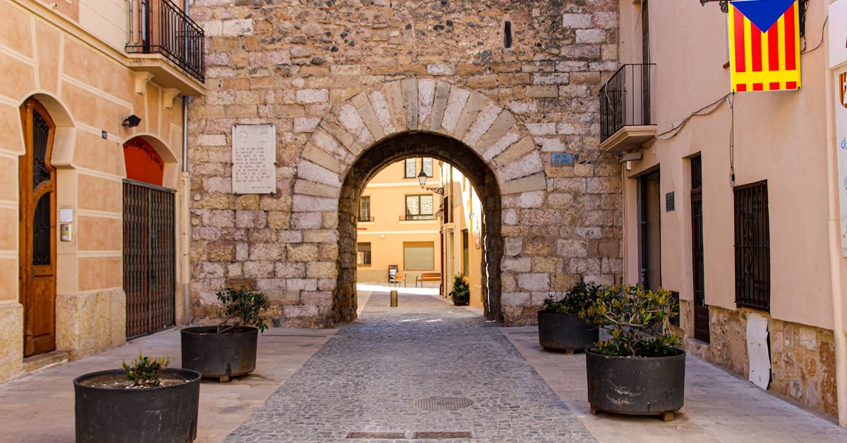 Charming cobblestone street with historic stone archway in Montblanc, Spain.