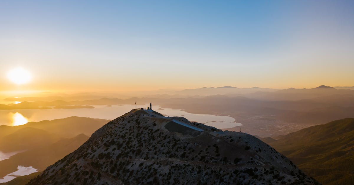 Stunning aerial perspective of a mountain peak under a golden sunrise reflecting on the sea.