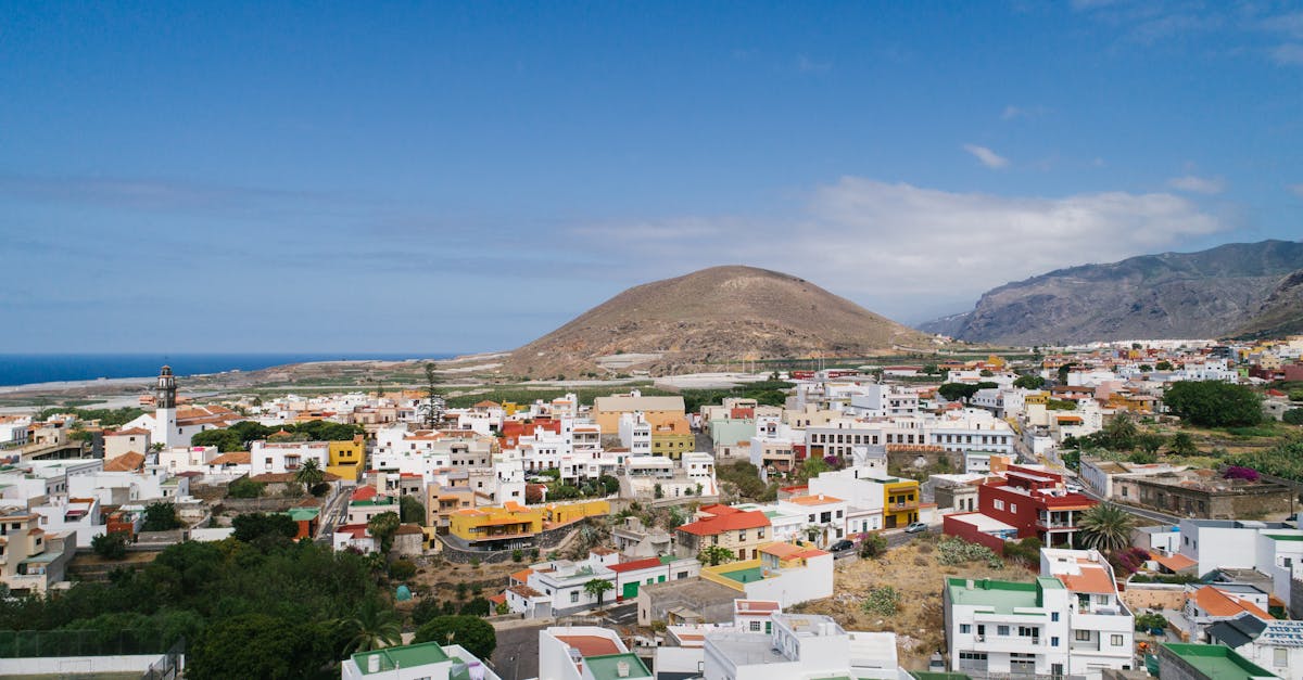 Aerial view of a vibrant seaside town with colorful rooftops nestled between hills and the ocean.