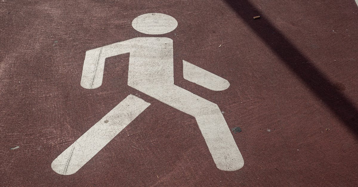 Close-up of a pedestrian symbol painted on a concrete sidewalk in urban setting.