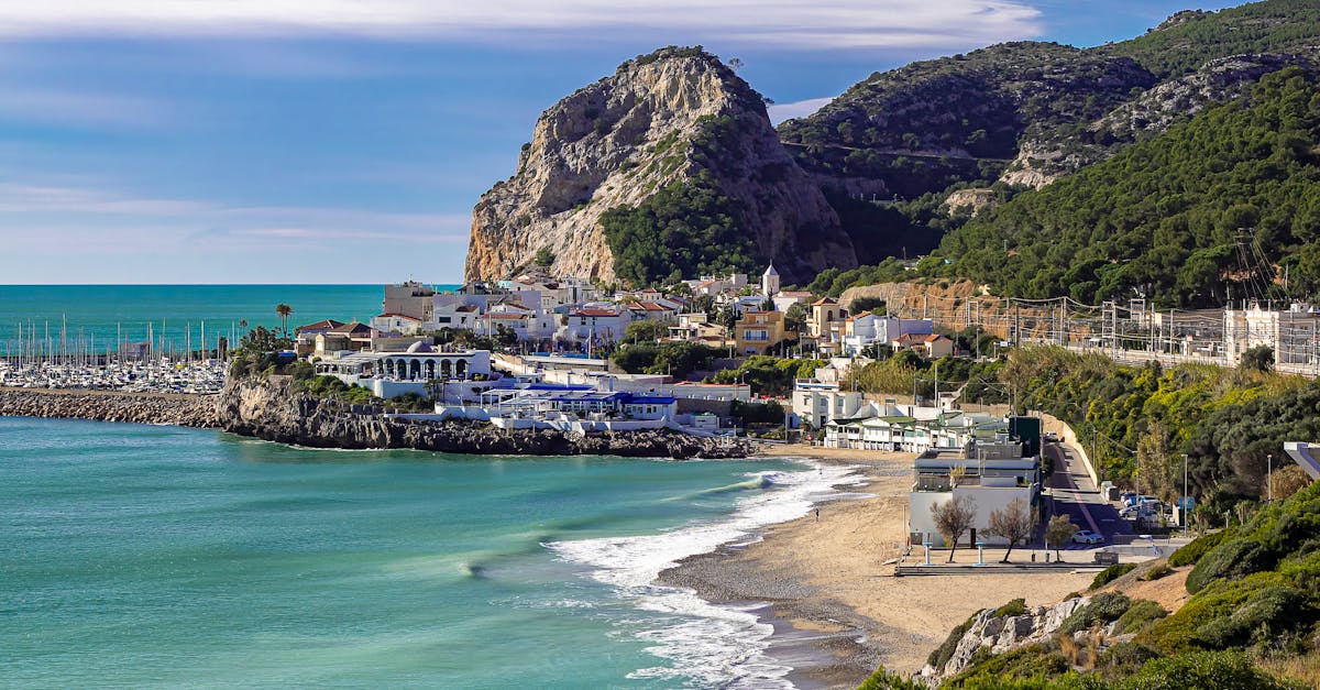 A stunning aerial view of Garraf Beach with azure sea, lush hills, and vibrant village in Spain.