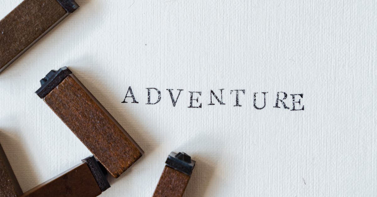 Wooden stamps form the word 'Adventure' on white textured canvas.