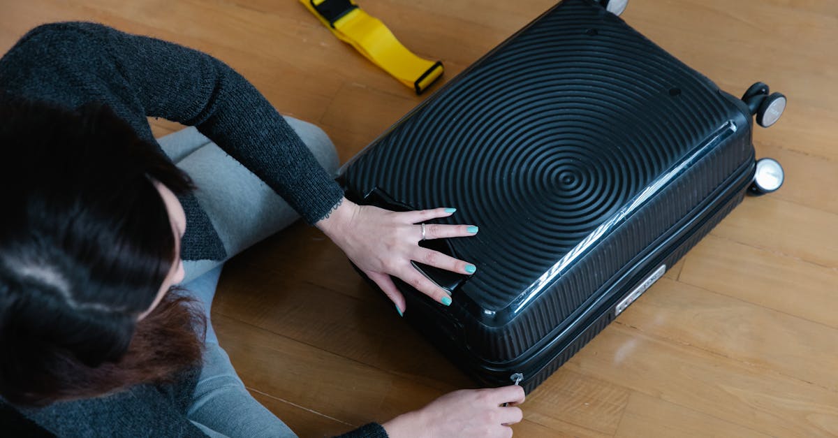 A woman preparing her suitcase for travel, sitting on a wooden floor indoors.