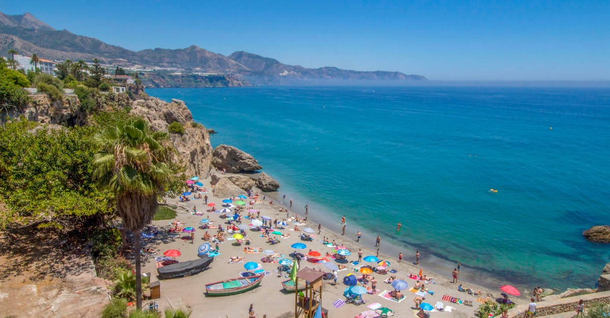 Colorful beach scene at Málaga with umbrellas and people enjoying the summer day.