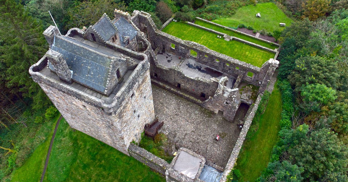 Explore the historic ruins of a medieval castle surrounded by lush greenery in Scotland.