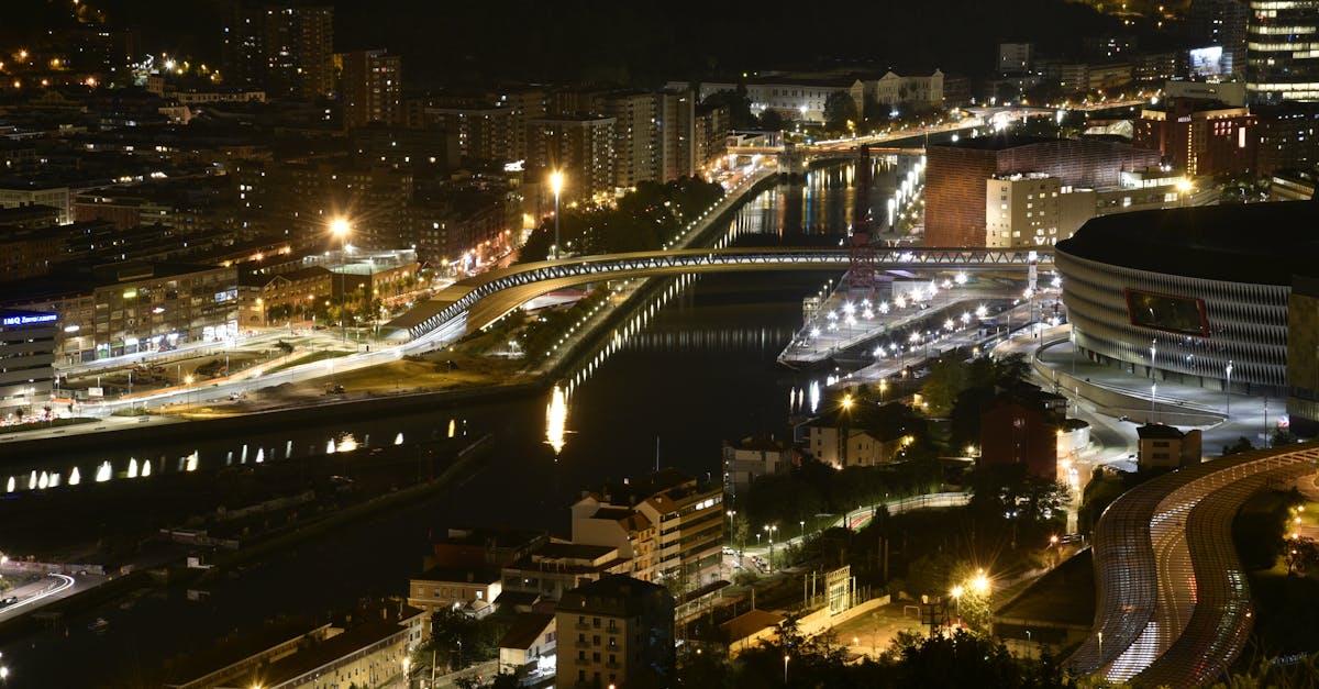 Panoramic view of a bustling city at night with glowing lights reflecting on the river.