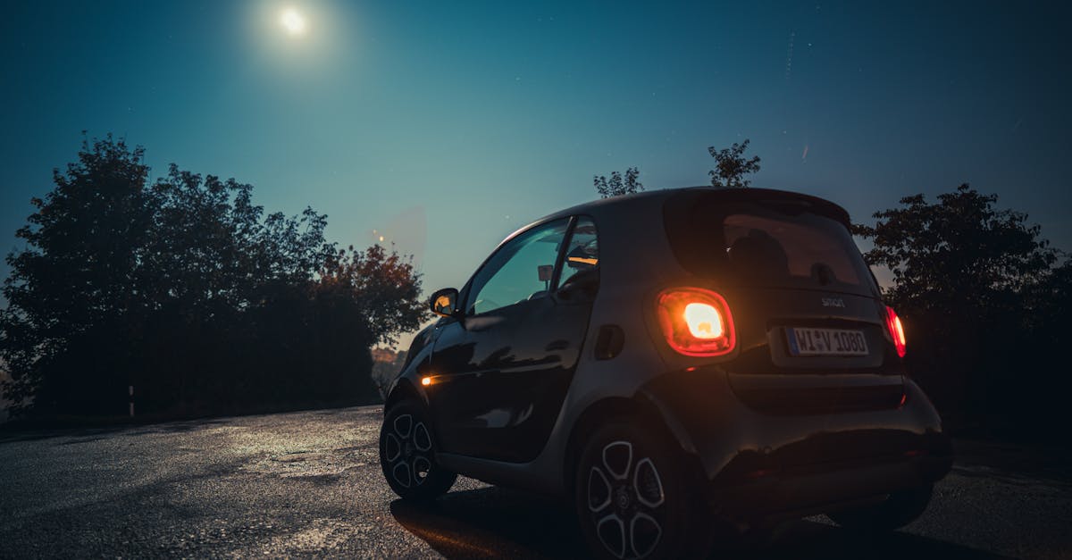A sleek electric Smart Forfour parked outdoors at night, illuminated by a bright moon and street lights.